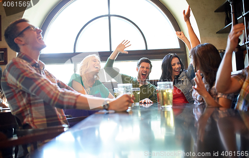 Image of friends with beer watching football at bar or pub