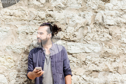 Image of man with smartphone at stone wall