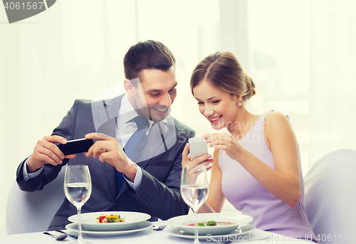 Image of smiling couple with appetizers and smartphones