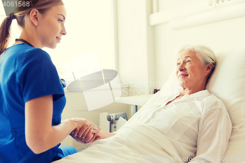 Image of doctor or nurse visiting senior woman at hospital