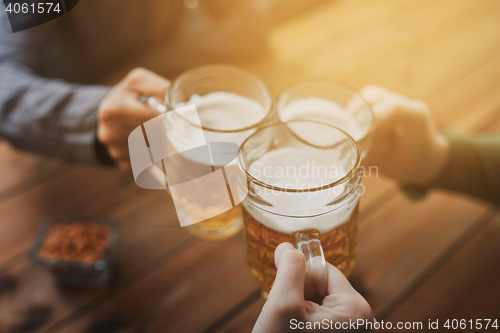 Image of close up of hands with beer mugs at bar or pub