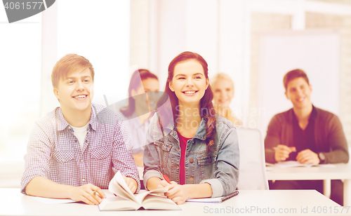 Image of two teenagers with notebooks and book at school