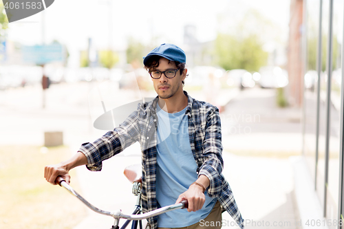 Image of young man with fixed gear bicycle walking in city