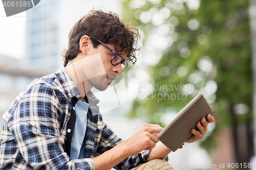 Image of man with tablet pc sitting on city street bench