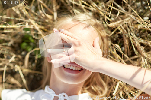 Image of happy young woman lying on cereal field