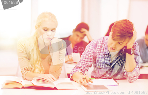 Image of tired students with tablet pc, books and notebooks