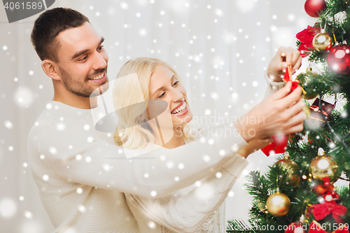 Image of happy couple decorating christmas tree at home