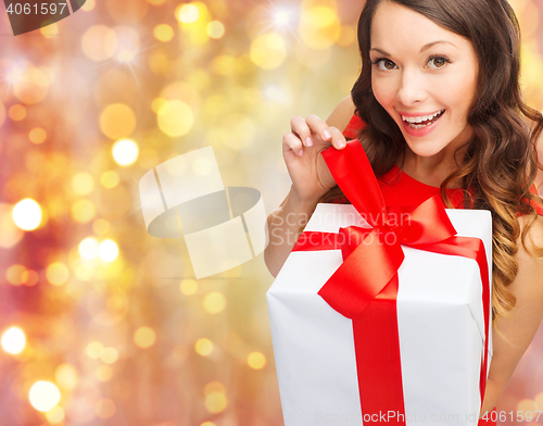 Image of smiling woman in red dress with christmas gift