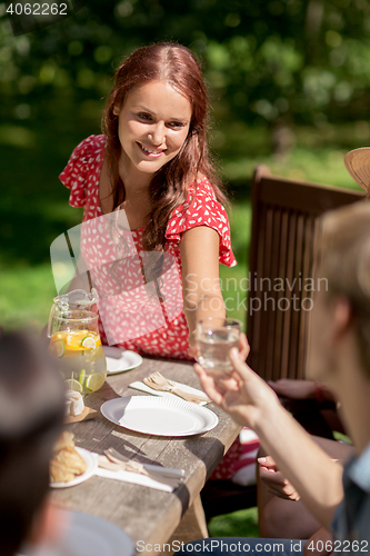 Image of happy friends having dinner at summer garden party