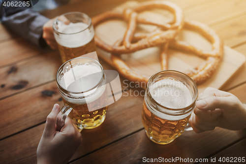 Image of close up of hands with beer mugs at bar or pub