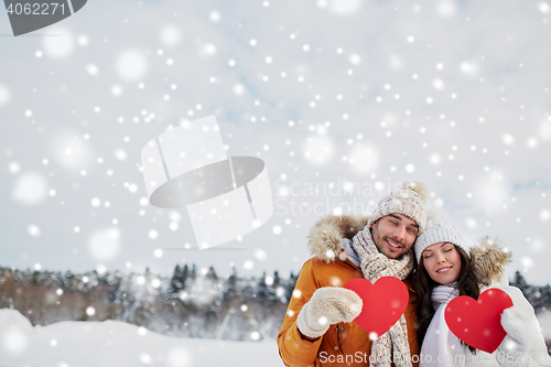 Image of happy couple with red hearts over winter landscape