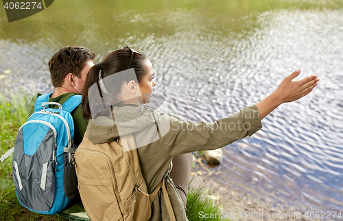 Image of couple with backpacks sitting on river bank