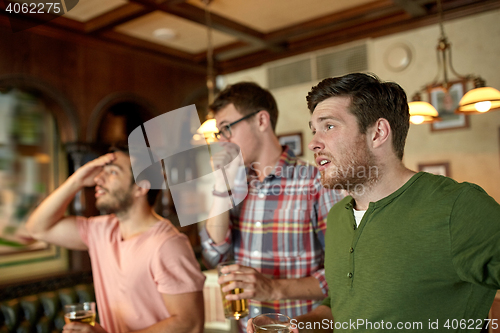 Image of friends with beer watching sport at bar or pub