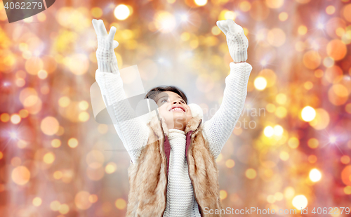 Image of happy little girl in earmuffs over holidays lights