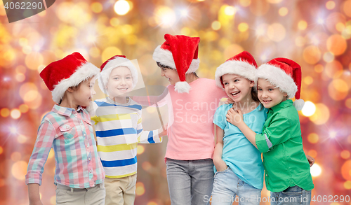 Image of happy little children in santa hats hugging