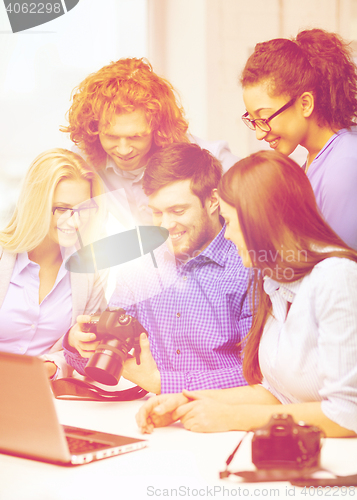 Image of smiling team with laptop and photocamera in office