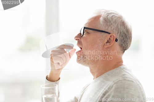 Image of senior man taking medicine pill at home