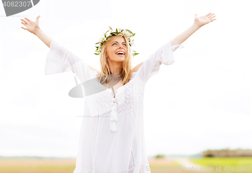 Image of happy young woman in flower wreath on cereal field