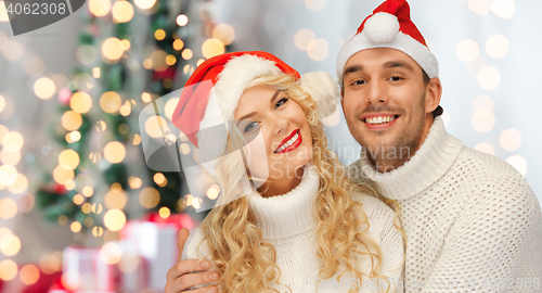 Image of happy family couple in sweaters and santa hats