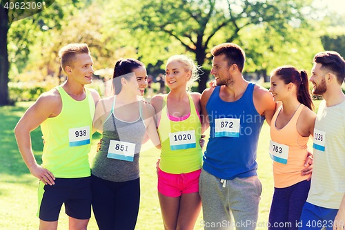 Image of happy friends or couple with racing badge numbers