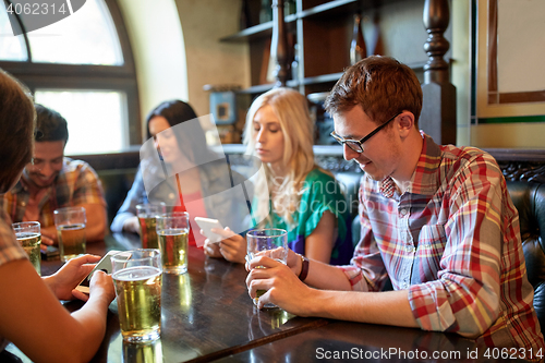 Image of friends with smartphones and beer at bar or pub