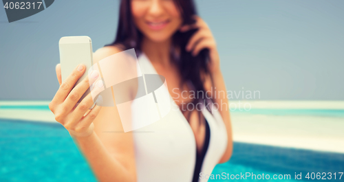 Image of young woman taking selfie with smartphone