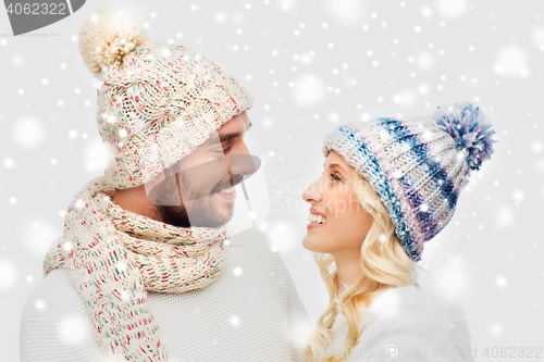 Image of smiling couple in winter clothes hugging over snow