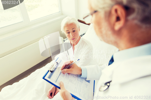 Image of senior woman and doctor with clipboard at hospital