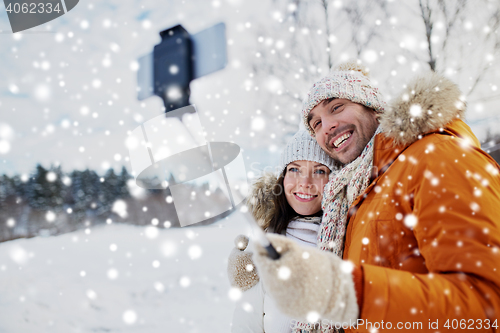 Image of happy couple taking selfie by smartphone in winter