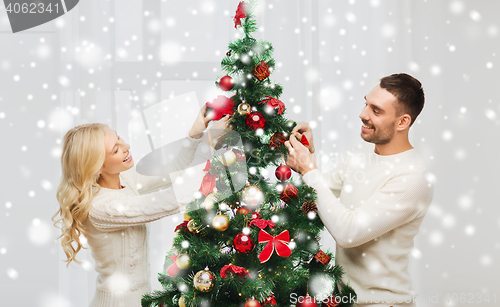 Image of happy couple decorating christmas tree at home