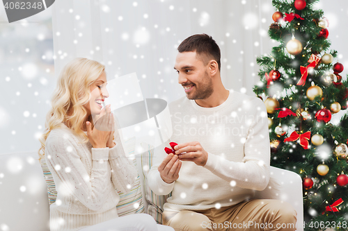 Image of man giving woman engagement ring for christmas