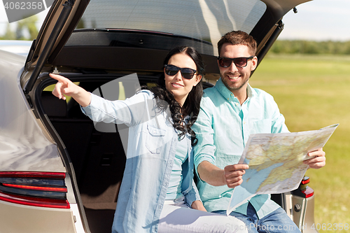 Image of happy man and woman with road map at hatchback car