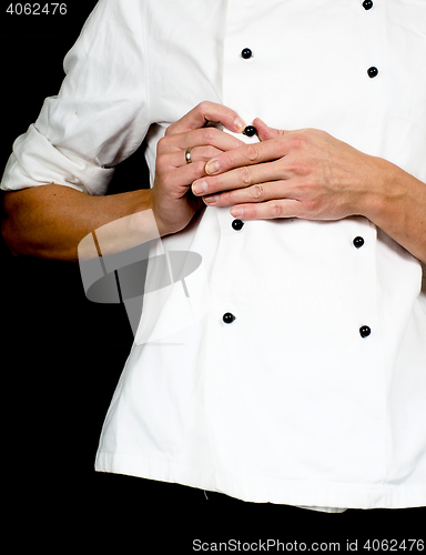 Image of Professional chef buttoning up a white chefs jacket towards blac