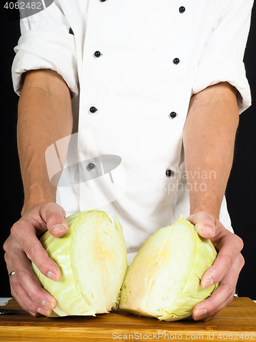 Image of Professional chef showing a cabbage cut into two pieces on a woo