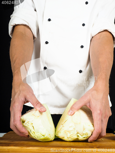 Image of Professional chef showing a cabbage cut into two pieces on a woo