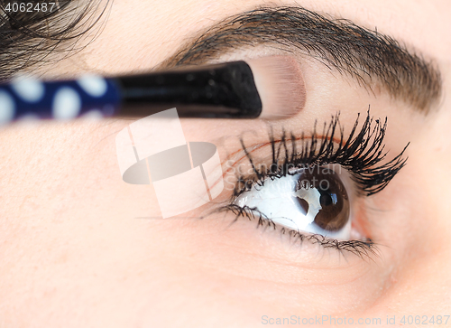 Image of Female lying final touch of makeup at extreme closeup