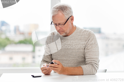 Image of senior man with glucometer checking blood sugar