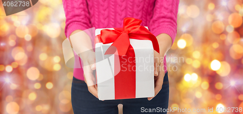 Image of close up of woman in pink sweater holding gift box