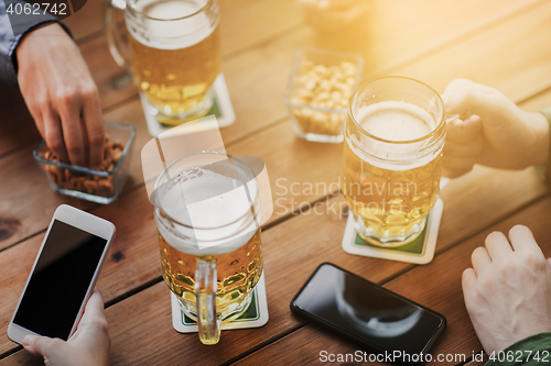 Image of close up of hands with smartphones and beer at bar