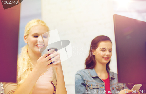 Image of two teens with smartphones in computer class