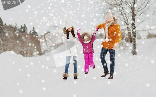 Image of happy family in winter clothes walking outdoors