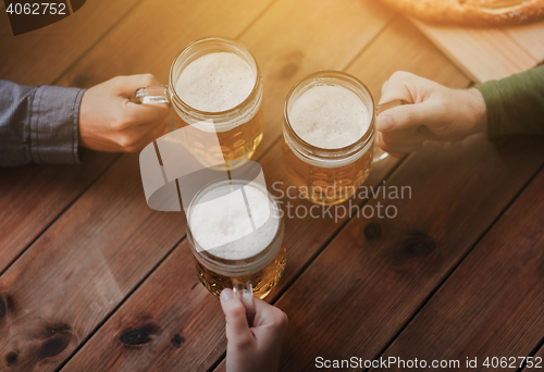 Image of close up of hands with beer mugs at bar or pub