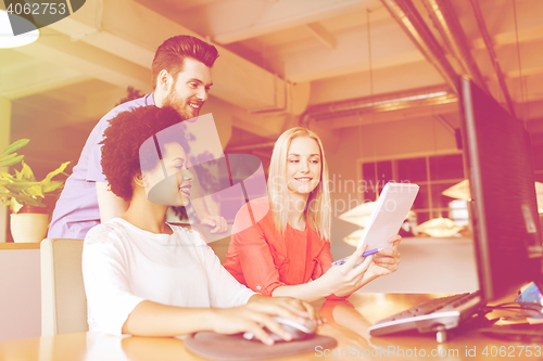 Image of happy creative team with computer in office