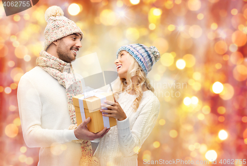 Image of smiling couple in winter clothes with gift box