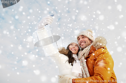 Image of happy couple taking selfie by smartphone in winter