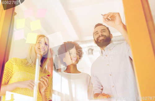 Image of happy creative team writing on stickers at office