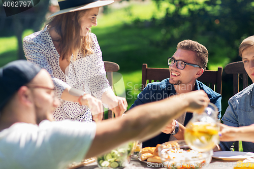 Image of happy friends having dinner at summer garden party