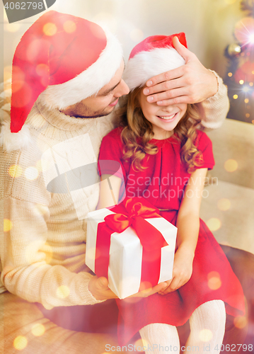 Image of smiling father surprises daughter with gift box