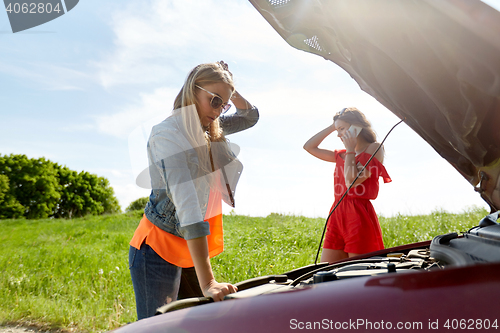 Image of women with open hood of broken car at countryside