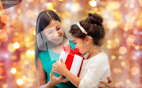 Image of happy mother and girl with gift box over lights